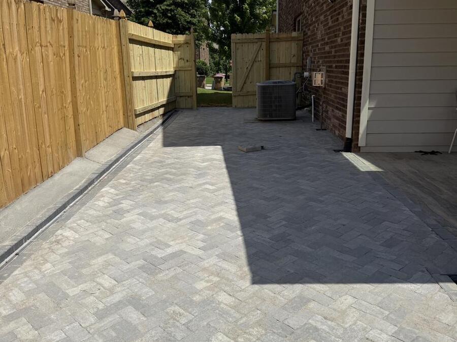 After: the side yard finished in grey herringbone pavers with a charcoal border running the length of the fence.