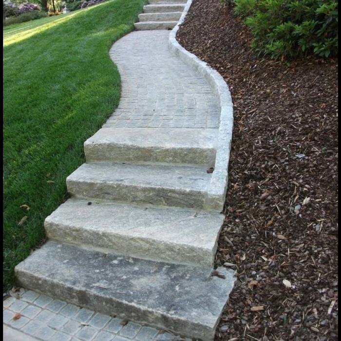 Granite stair treads and a paver path curving between a lawn and a mulched planting bed.