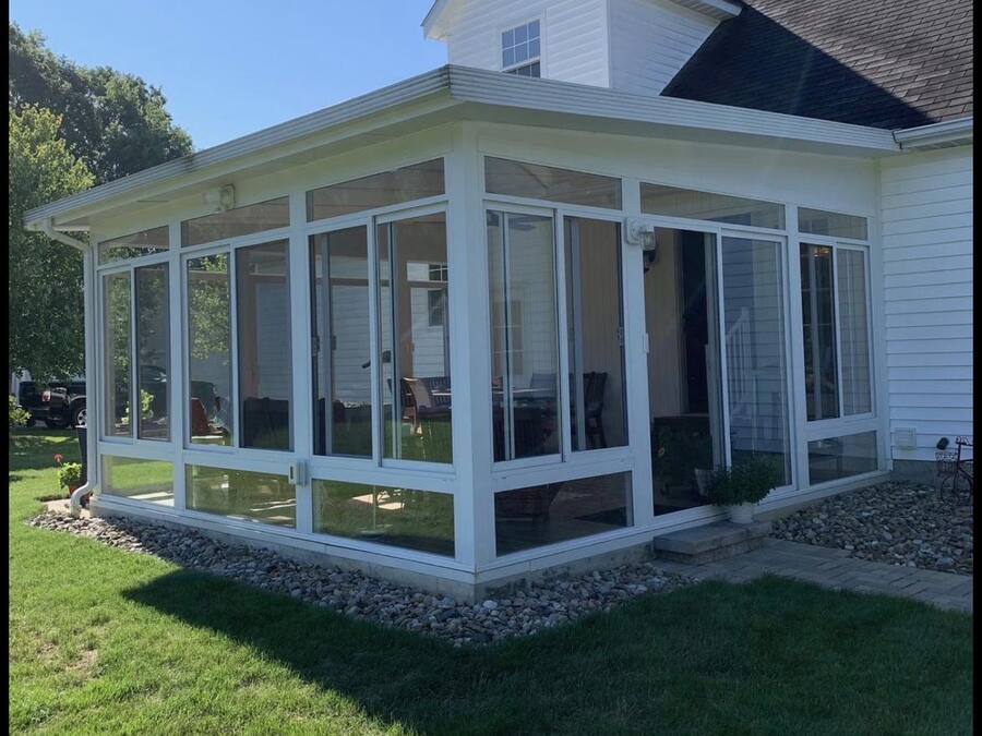 Completed glass sunroom addition with white framing on the rear elevation of a home.