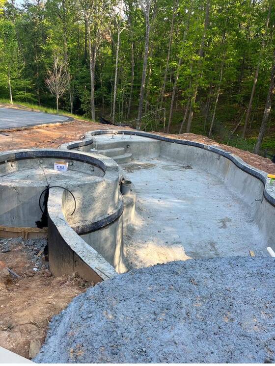 Pool shell excavated and formed, with plumbing runs set before the shell is placed.