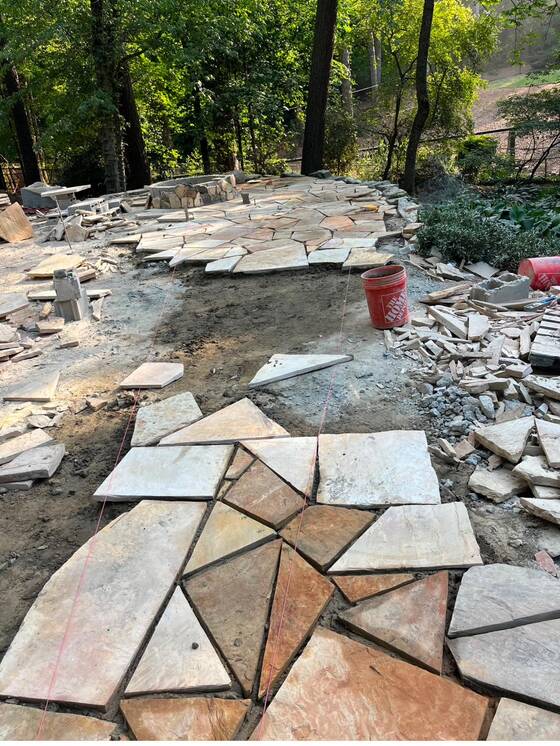 Irregular flagstone pieces dry-laid and fitted on a prepared base before setting.