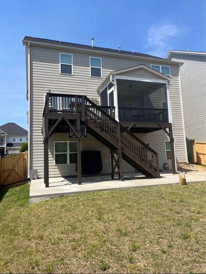 Before: the existing rear elevation with a weathered stained deck and open stair.