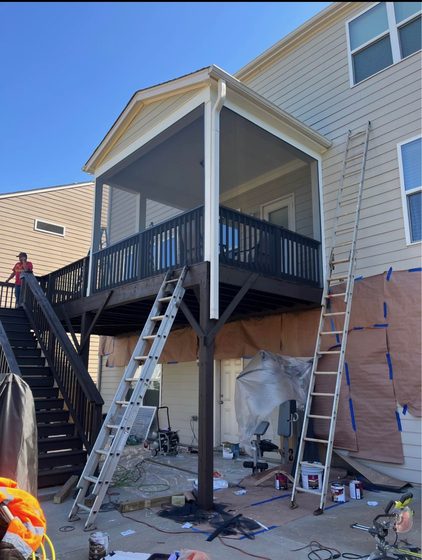 In progress: crew working the rear elevation with ladders set and the patio below masked off.